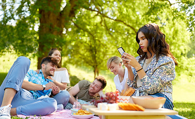 Image showing woman using smartphone at picnic with friends