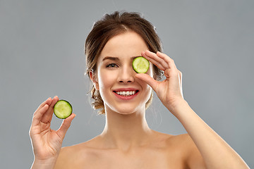 Image showing smiling woman with cucumber over grey background