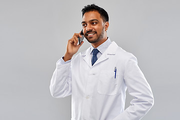 Image showing smiling indian male doctor calling on smartphone