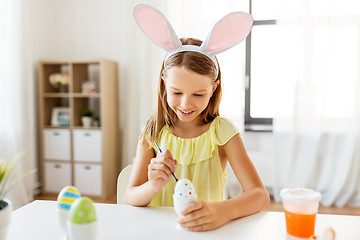 Image showing happy girl coloring easter eggs at home