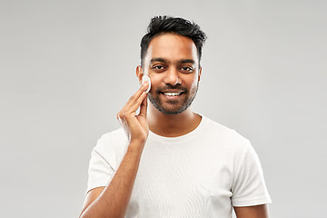 Image showing smiling indian man cleaning face with cotton pad