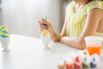 Image showing close up of girl coloring easter egg by paintbrush