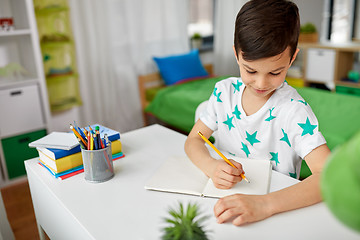 Image showing happy boy writing or drawing to notebook at home