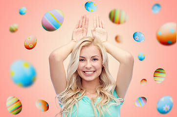 Image showing happy smiling young woman making easter bunny ears