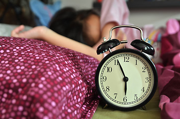 Image showing Pretty girl sleeping on the background of a retro alarm clock