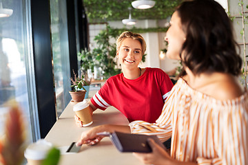 Image showing female friends paying by credit card at cafe