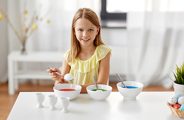 Image showing girl coloring easter eggs by liquid dye at home