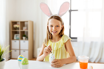 Image showing happy girl coloring easter eggs at home