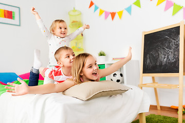 Image showing happy little kids having fun in bed at home