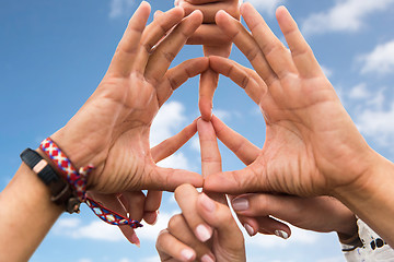 Image showing hands of hippie friends making peace sign over sky