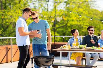 Image showing happy friends grilling at bbq party on rooftop