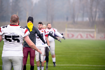 Image showing american football players stretching and warming up