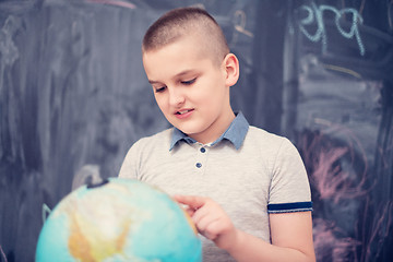 Image showing boy using globe of earth in front of chalkboard