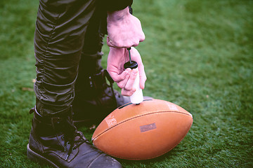 Image showing man pumping air into american football ball
