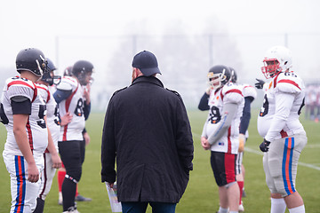 Image showing american football players discussing strategy with coach