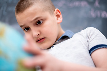 Image showing boy using globe of earth in front of chalkboard