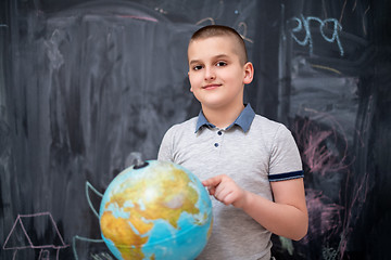 Image showing boy using globe of earth in front of chalkboard