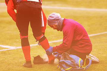 Image showing Sports doctor using freezing spray while treating injured sportm