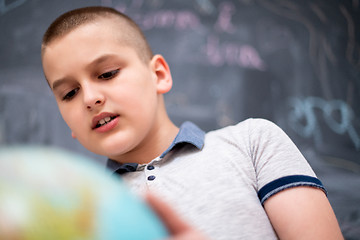 Image showing boy using globe of earth in front of chalkboard