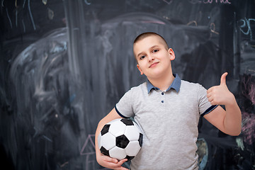 Image showing happy boy holding a soccer ball in front of chalkboard