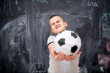 Image showing happy boy holding a soccer ball in front of chalkboard