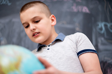 Image showing boy using globe of earth in front of chalkboard