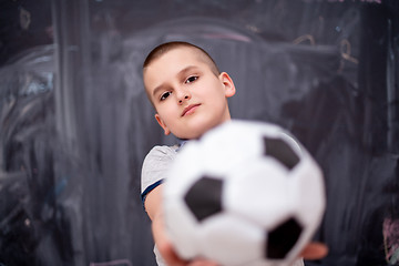 Image showing happy boy holding a soccer ball in front of chalkboard