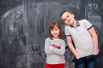 Image showing boy and little girl standing in front of chalkboard