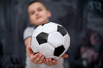 Image showing happy boy holding a soccer ball in front of chalkboard