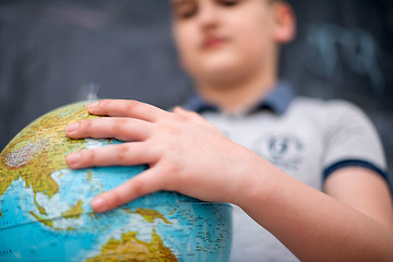 Image showing boy using globe of earth in front of chalkboard