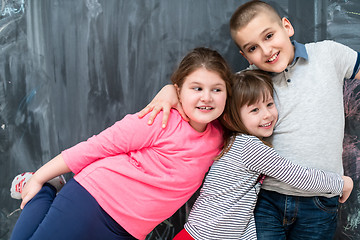 Image showing group of kids hugging in front of chalkboard