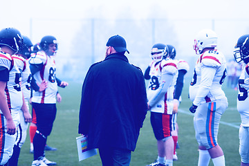 Image showing american football players discussing strategy with coach