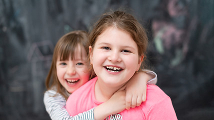 Image showing little girls hugging in front of chalkboard