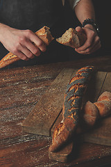 Image showing Male hands break the baguette