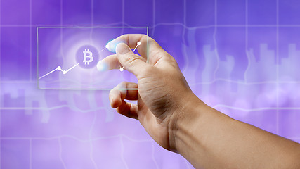 Image showing A man holds a glass screen with a bitcoin symbol and a crypto currency graph