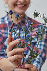 Image showing Happy girl holding a flower eryngium