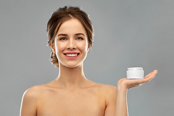 Image showing happy young woman holding jar of cream