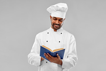 Image showing happy male indian chef reading cookbook