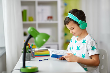 Image showing boy in headphones with textbook learning at home