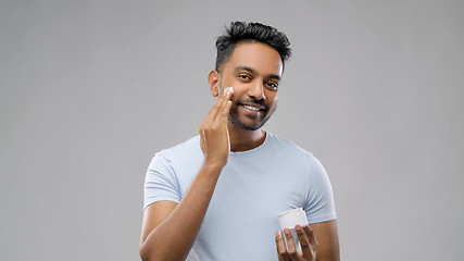 Image showing happy indian man applying cream to face