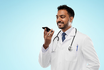 Image showing smiling indian male doctor calling on smartphone