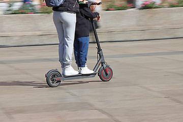 Image showing Mother and son riding electric kick scooter at the city square