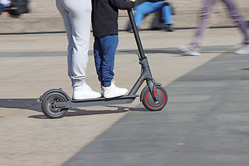 Image showing Mother and son riding electric kick scooter at the city square
