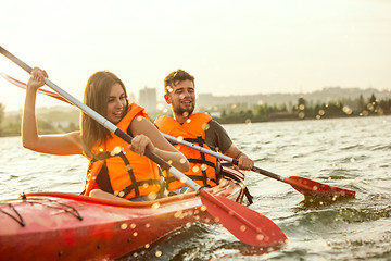 Image showing Happy couple kayaking on river with sunset on the background