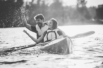 Image showing Happy couple kayaking on river with sunset on the background