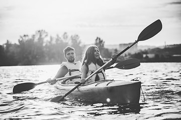 Image showing Happy couple kayaking on river with sunset on the background