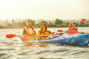 Image showing Happy friends kayaking on river with sunset on the background