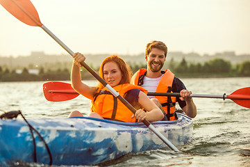 Image showing Happy couple kayaking on river with sunset on the background