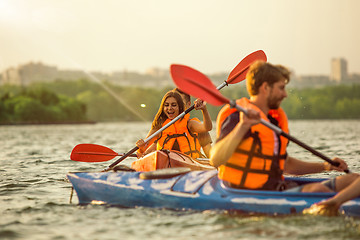 Image showing Happy friends kayaking on river with sunset on the background