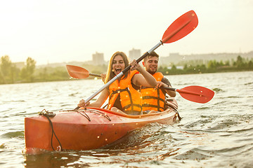 Image showing Happy couple kayaking on river with sunset on the background